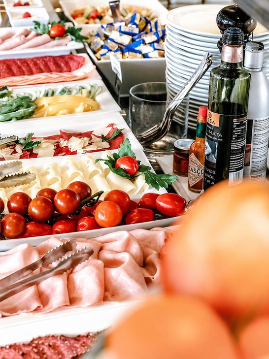 Mesa de desayuno buffet americano con fruta fresca, panificados, café y jugo